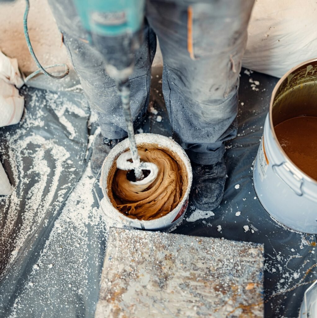 Professional worker mixes two chemical compounds in the metal bucket using the mixer